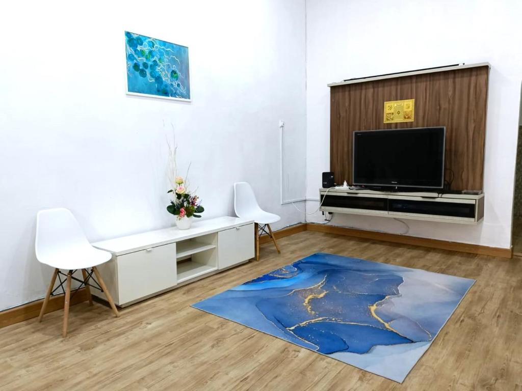 古来YK Homestay的一间配有电视和蓝色地毯的客厅