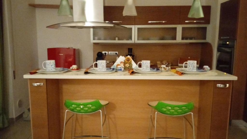 马泰拉Sweet holidays的一个带两个绿色凳子的厨房岛