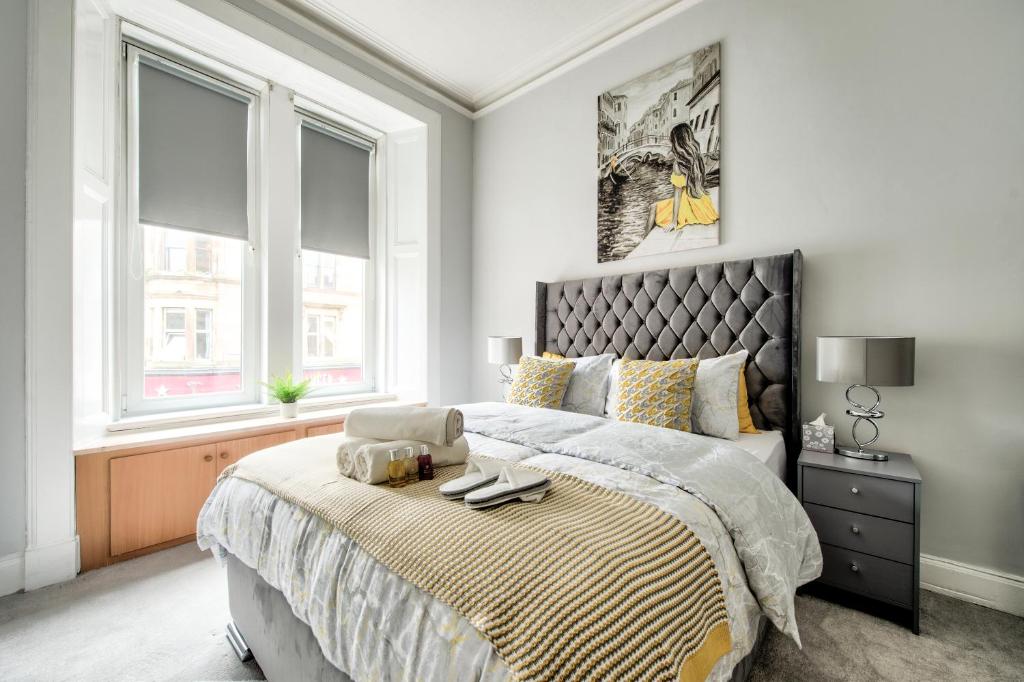 格拉斯哥Two Bed Stylish Apartment in Heart of West End的一间卧室设有一张大床和两个窗户。