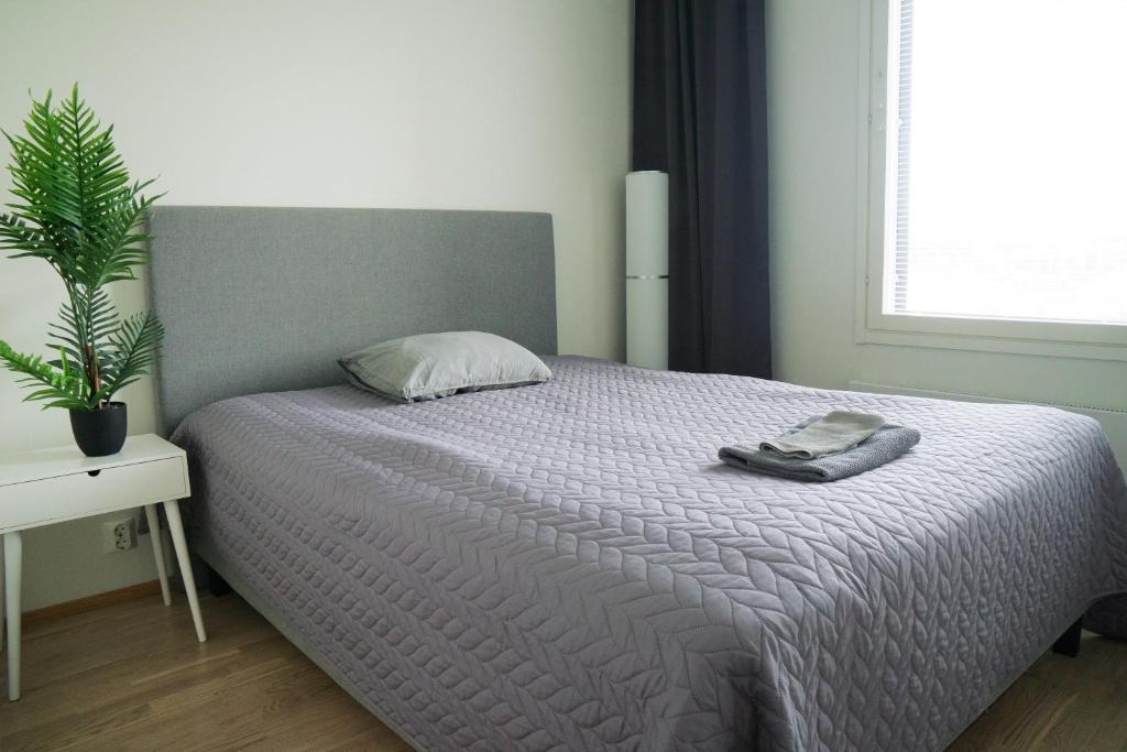 奥卢Lovely 2R apartment的一间卧室配有一张带毯子和植物的床