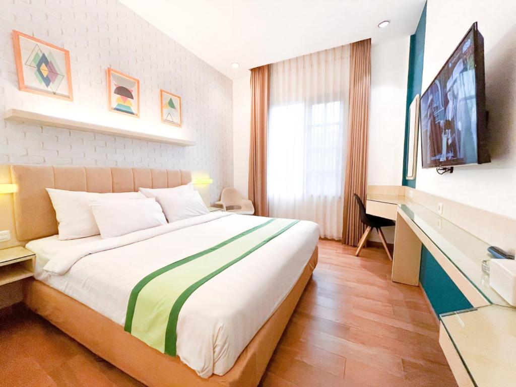 普禾加多Hotel Wisata Niaga Campus的配有一张床和一台平面电视的酒店客房