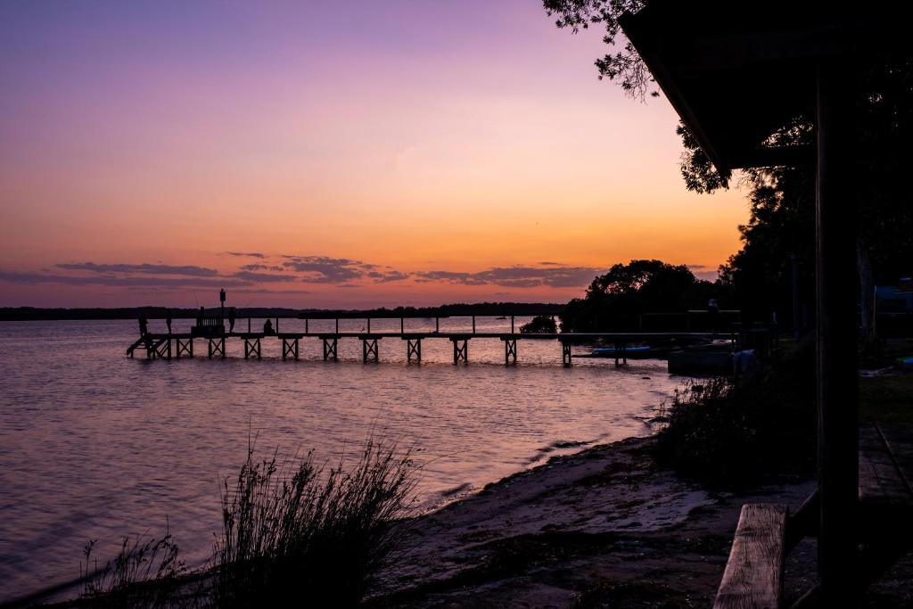Lemon Tree PassageKoala Shores Holiday Park的水面上的码头,背景是日落