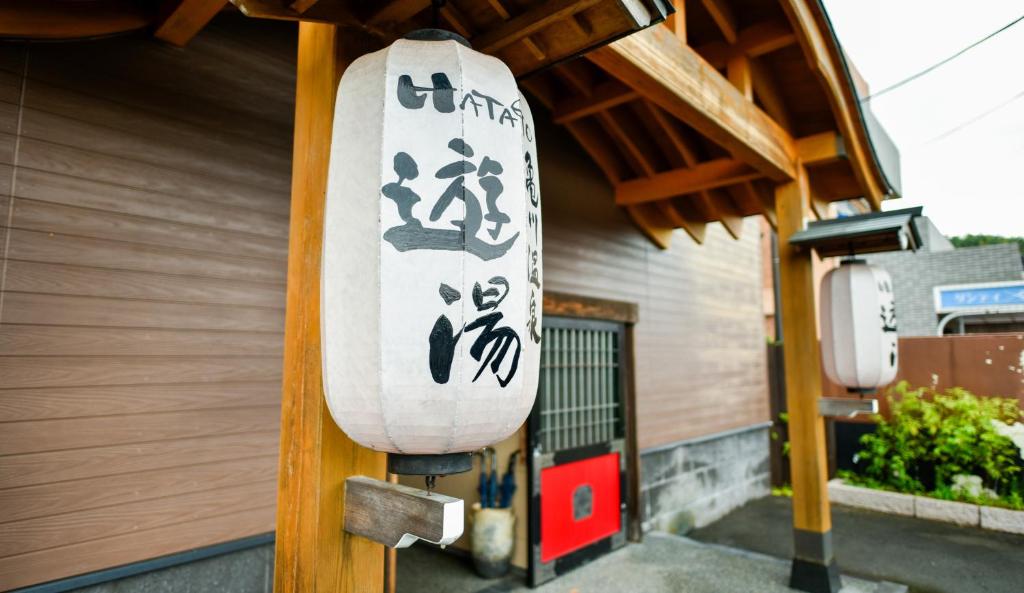 别府Kamegawa Onsen HATAGO Yuyu的建筑一侧的冲浪板,上面写有亚洲文字
