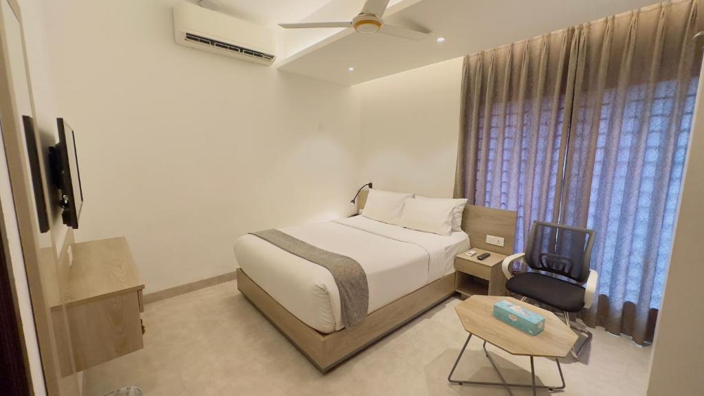 达卡Priyo Nibash Stylish Residential Hotel的一间卧室配有一张床、一台电视和一把椅子