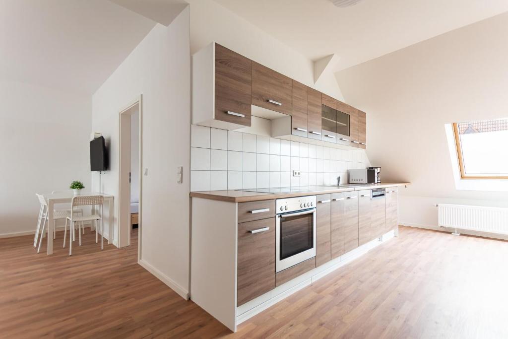 杜伊斯堡T&K Apartments - DUISBURG - Frisch renovierte 4 Zimmer Maisonetten mit Privatparkplätzen的厨房设有白色的墙壁和木制橱柜。