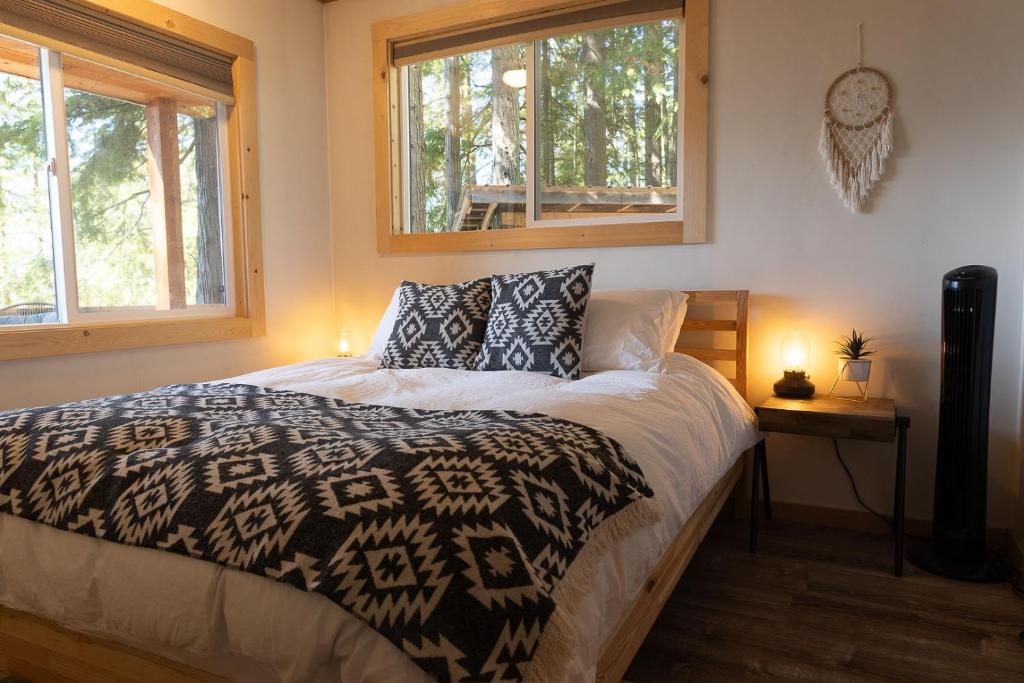 纳卡斯普Kootenay Lakeview Retreats - Forest Cabin的一间卧室设有一张床和两个窗户。