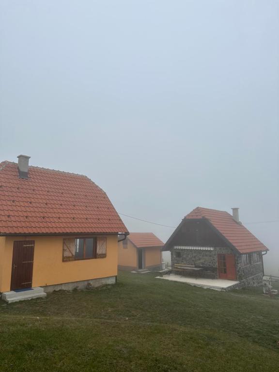 GradacVikendice Šušić的一座黄色的房子,有红色的屋顶和院子