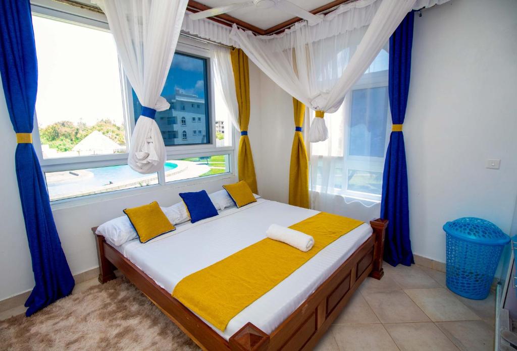 马林迪Kijani Suites的一间卧室配有一张带蓝色窗帘的床和一扇窗户