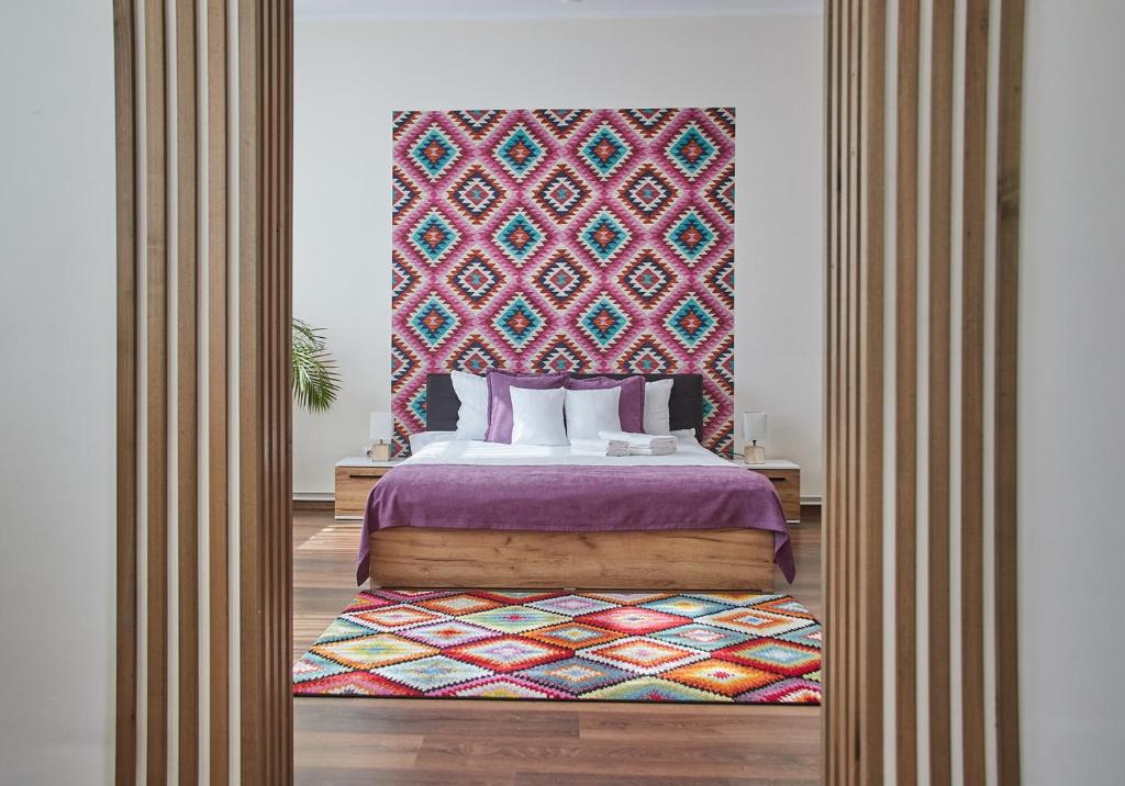 阿尔巴尤利亚CONFORT HOUSE PLUS的一间卧室配有一张特大号床和色彩缤纷的床头板