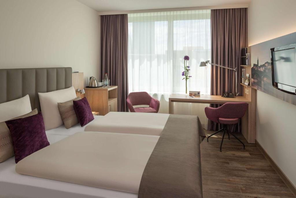 巴塞尔Essential by Dorint Basel City的酒店客房设有一张大床和一张书桌。