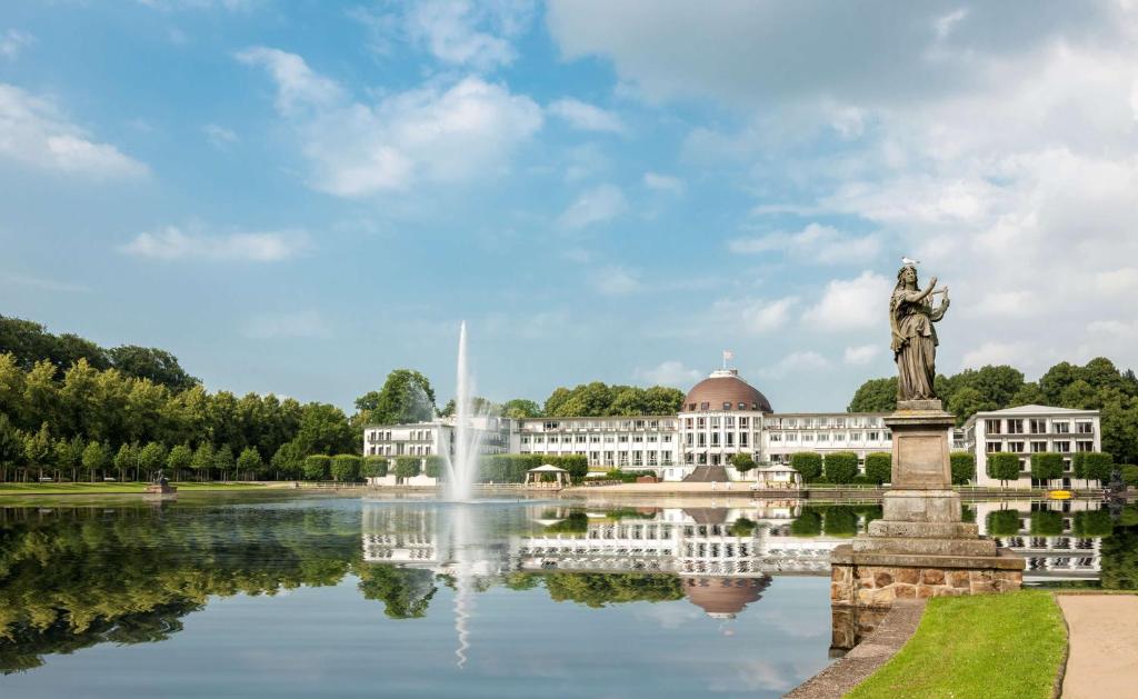 不莱梅Parkhotel Bremen – ein Mitglied der Hommage Luxury Hotels Collection的一座建有雕像的建筑,位于湖前,设有喷泉