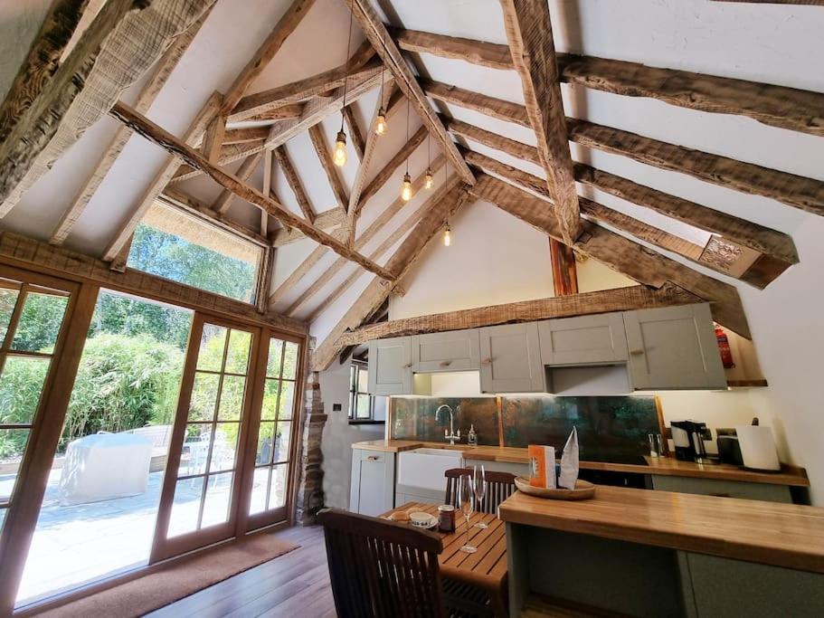 科夫堡Little Thatch的厨房配有木桌和一些窗户。