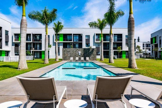 巴利托Ballito Luxury Apartment的一座建筑前的游泳池,里面设有椅子和棕榈树