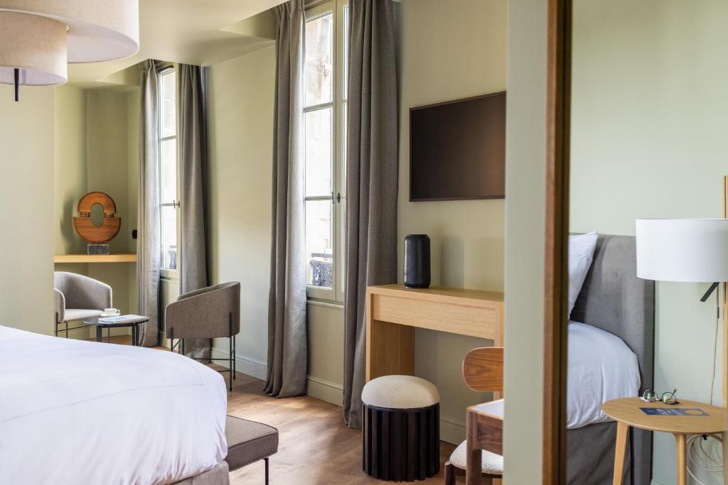 圣艾米隆Hotel Porte Brunet的酒店客房带一张床、一张桌子和椅子