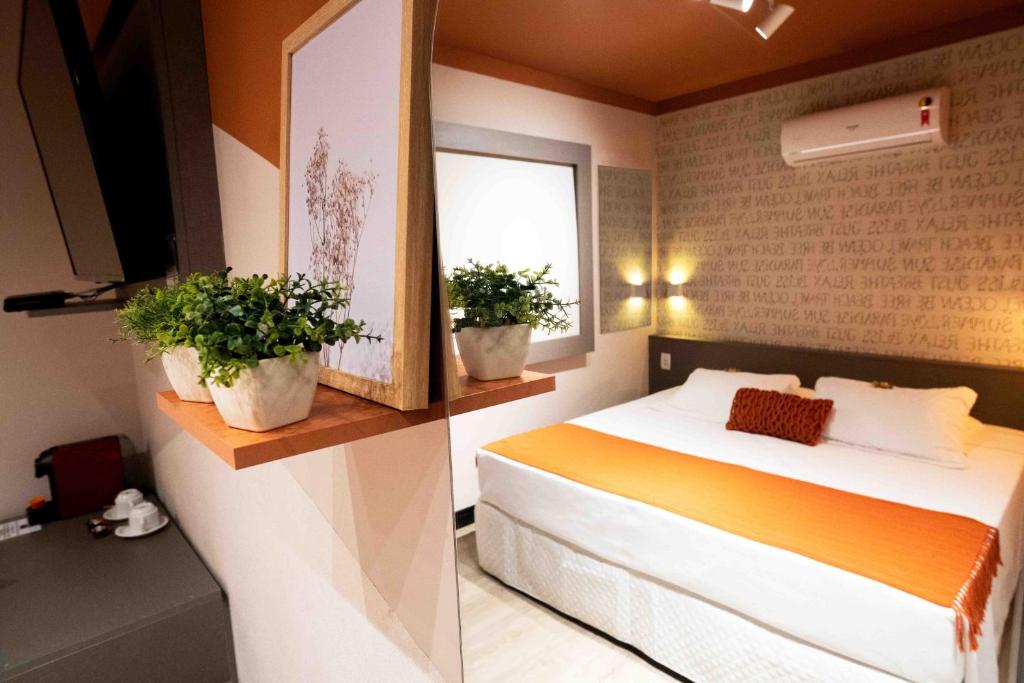 巴拉奈里奥-坎布里乌Camboriú Praia Hotel的一间卧室配有一张床和两盆植物