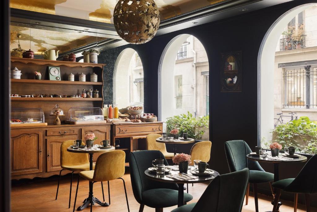 巴黎Albert's Hotel的一间设有桌椅的餐厅,位于带窗户的房间内