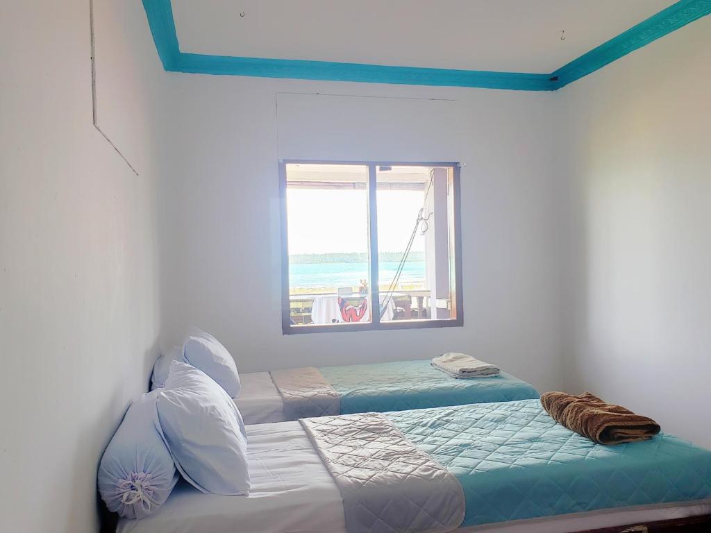 LagudriRaffiel Nias的一间卧室设有两张单人床和一个窗户。