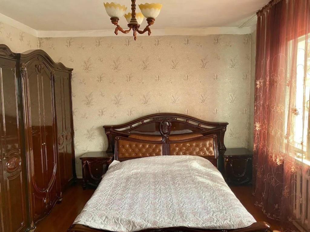 阿拉木图Room in the house, with mountain views and squirrels in the yard的一间卧室配有一张木床和吊灯。