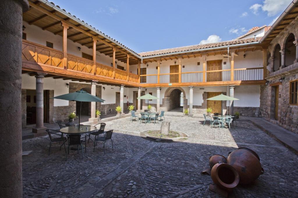 库斯科提阿瓦非凡库斯科中心酒店的一个带桌椅和遮阳伞的户外庭院。