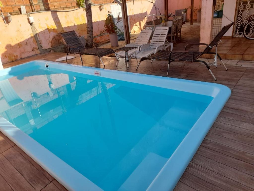 瓜鲁雅Aconchego的蓝色的游泳池配有椅子和桌子