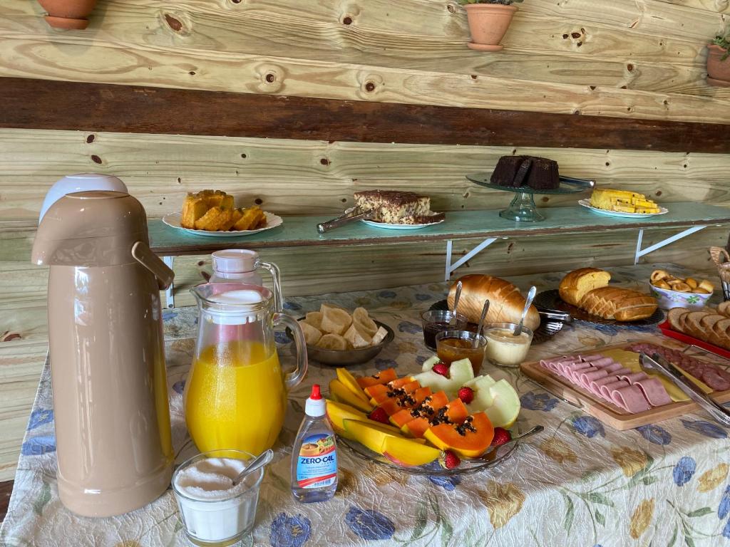 大普拉亚Pousada & Camping Nativos dos Canyons的一张桌子,上面有早餐食品和一壶橙汁