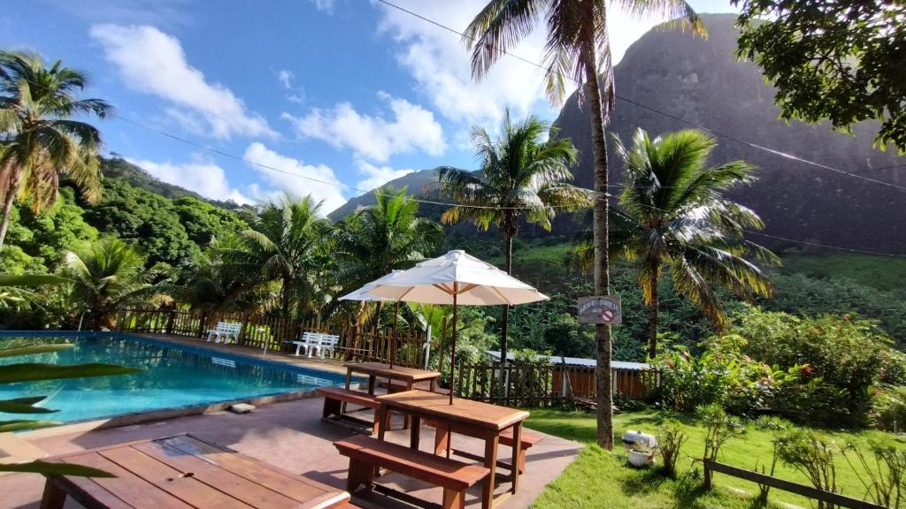 瓜拉派瑞Pousada Moinho D'água的一个带游泳池和带遮阳伞的桌子的度假胜地