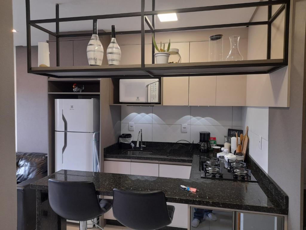 本图贡萨尔维斯Apartamento bem localizado的厨房配有黑色台面和冰箱