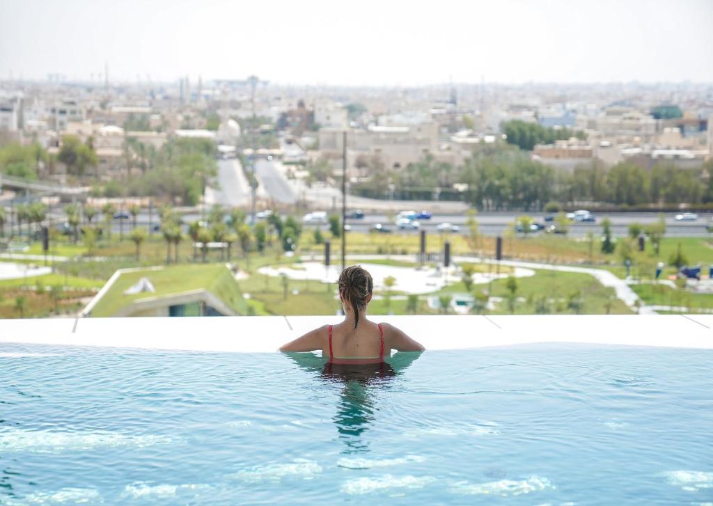 科威特科威特布尔阿沙哑四季酒店 的游泳池里的一个女人,看着城市