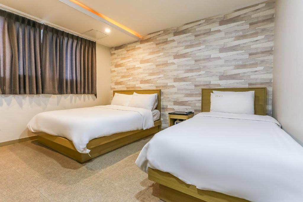 济州市Aliba Hotel的一间卧室设有两张床和石墙