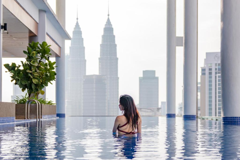 吉隆坡The Colony & The Luxe, Kuala Lumpur by Canopy Lives的坐在城市无边游泳池中的女人