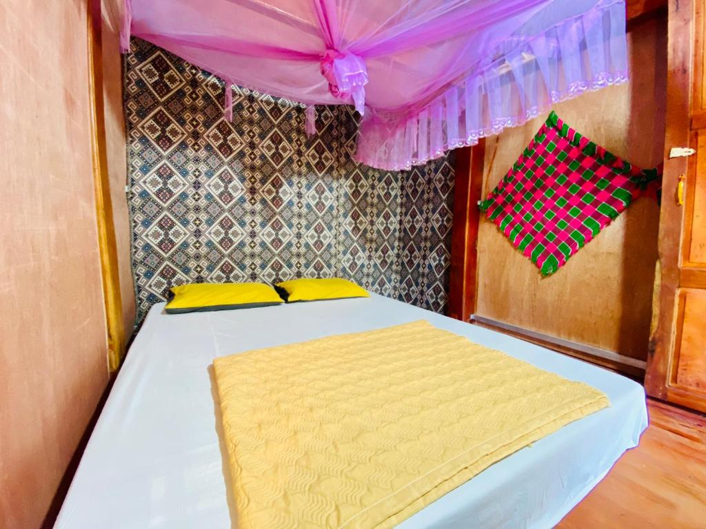 Làng CacDu Già Coffee View Homestay的一张带黄色枕头和紫色天蓬的床