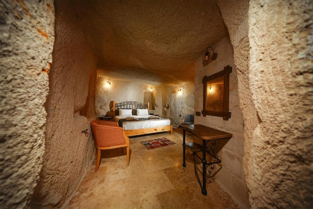 格雷梅Caverna Hotel Premium Caves的洞穴内一间卧室,配有一张床和一张桌子