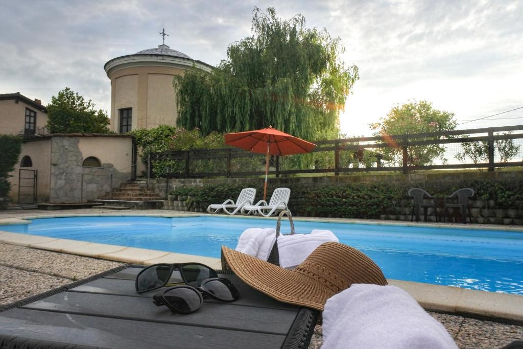 卡利亚诺阿谮达阿格里科拉巴罗农家乐的一把帽子和一对太阳镜,一个遮阳伞在游泳池旁边
