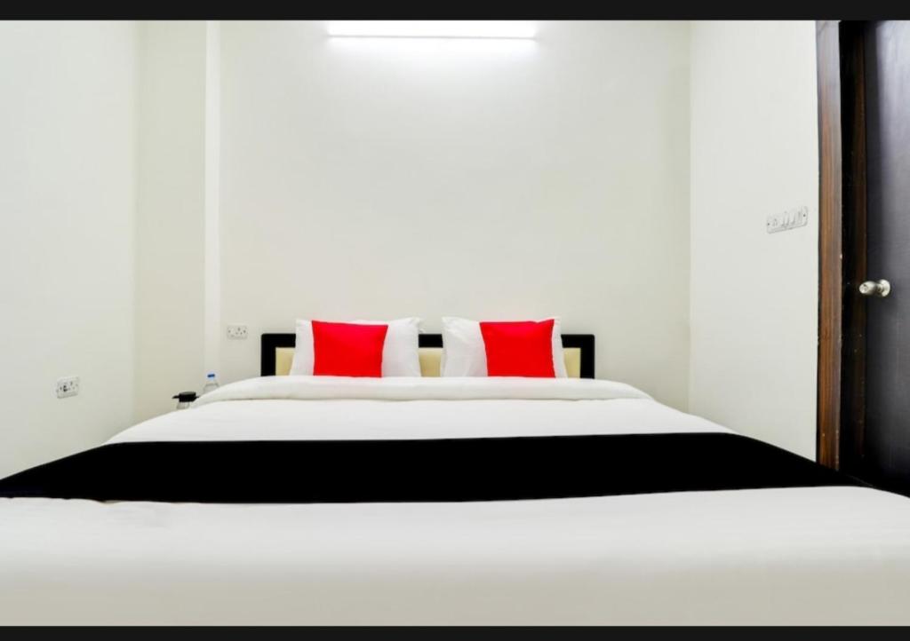 勒克瑙Nilansh homes and hotels的卧室配有带红色枕头的大型白色床