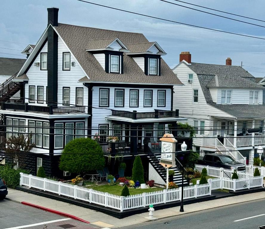 大洋城大西洋之家住宿加早餐旅馆的一座白色的大房子,前面有一个钟
