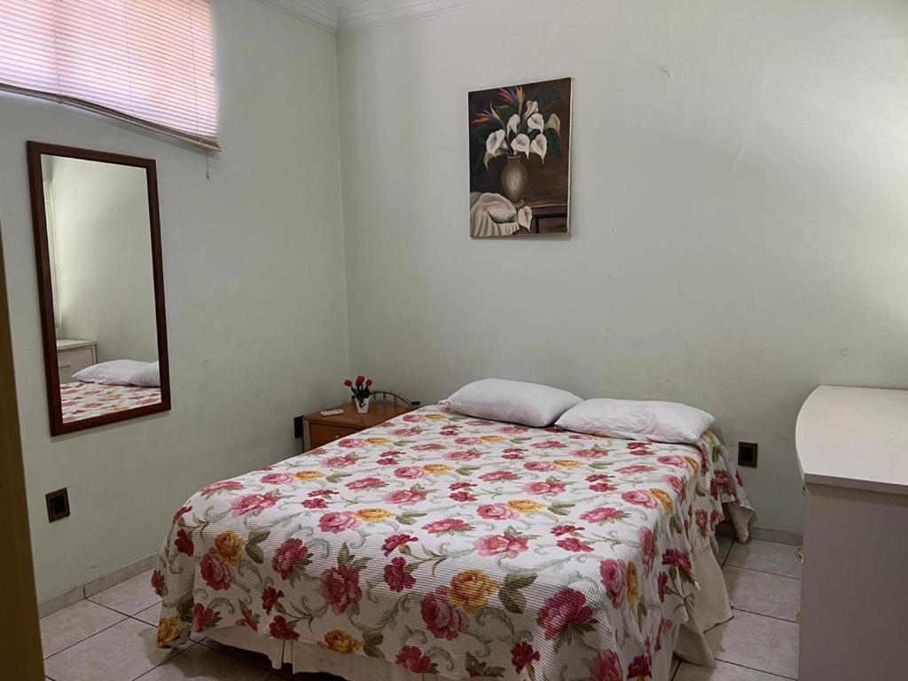 库亚巴Casa 3 suítes no centro de Cuiabá的一间卧室配有一张带花卉床罩和镜子的床