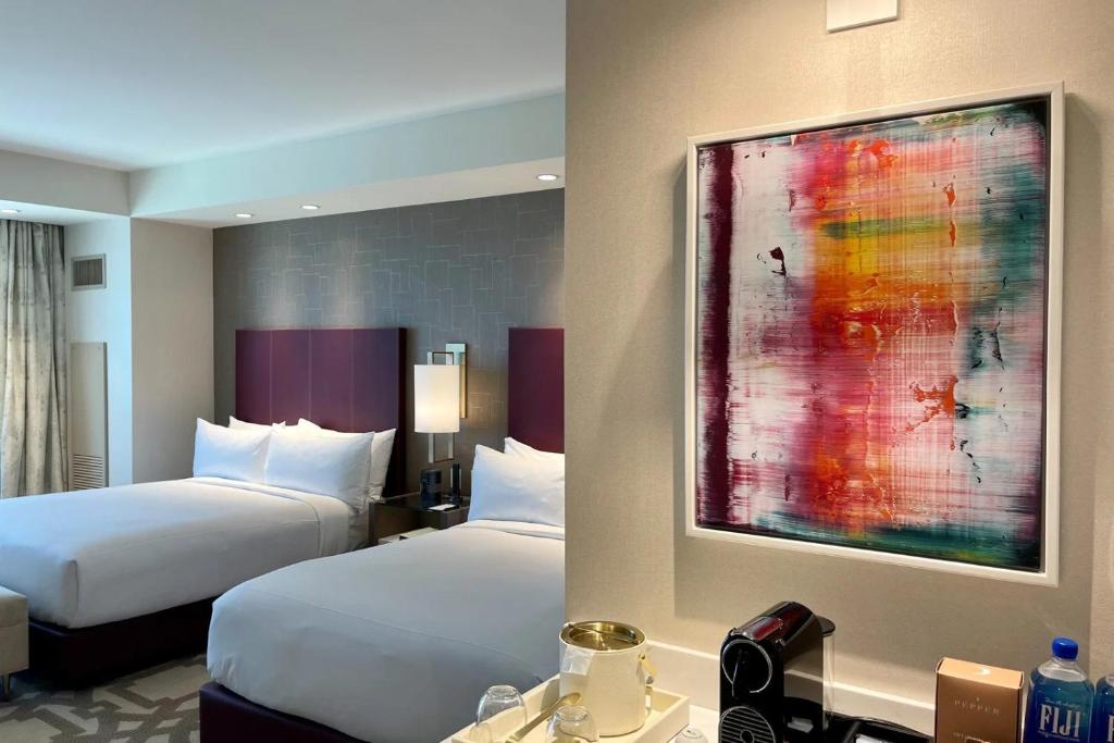 拉斯维加斯Elegant Stay at Resorts World Strip Las Vegas的酒店客房设有两张床,墙上挂有绘画作品