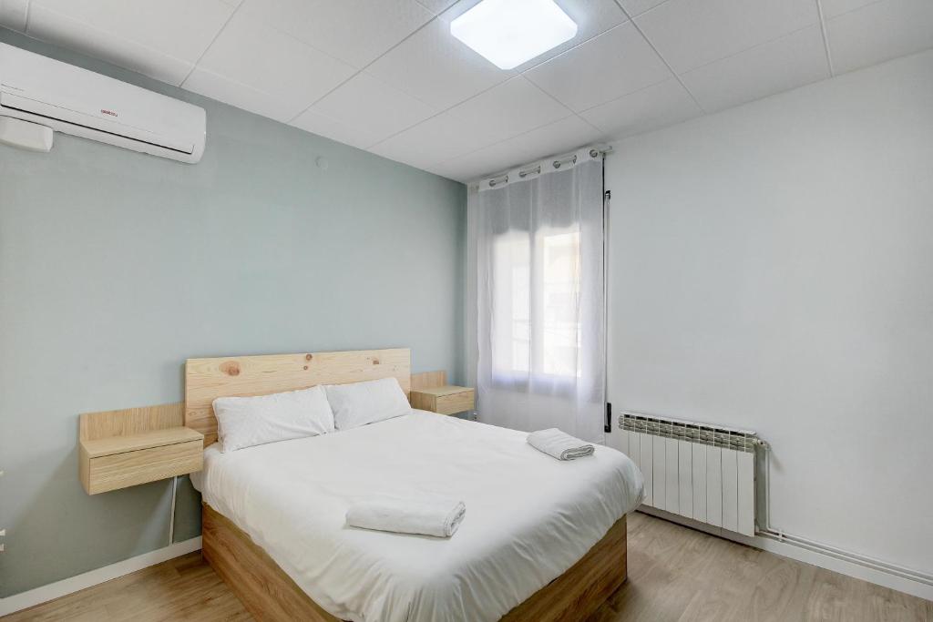圣阿德里安-德贝索斯Barcelona Beach Vibes的一间卧室配有一张带白色床单的床和一扇窗户。