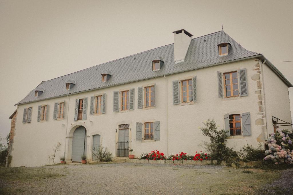 莫南Domaine de Berducq的一座白色的大房子,前面有红花