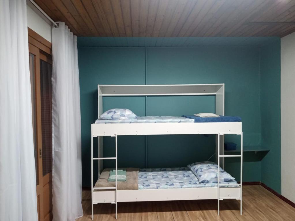 格拉玛多Casinha de Gramado的蓝色墙壁的客房内的双层床