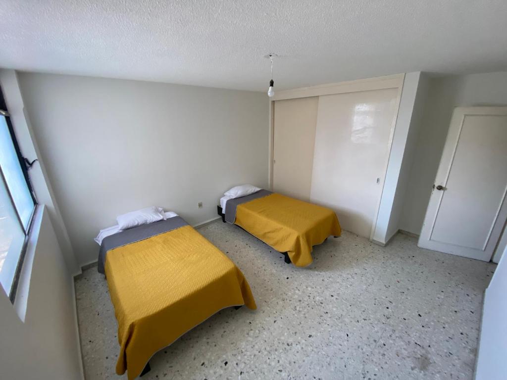 莱昂BaW Mateos 809P的小客房内的两张床,配有黄色床单
