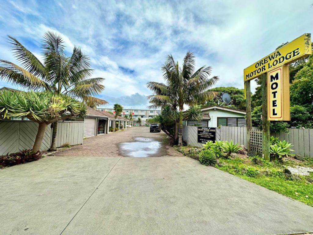 奥雷瓦Orewa Motor Lodge的一条棕榈树街道和汽车旅馆标志