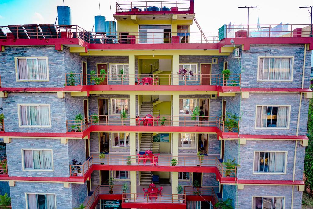 博卡拉Hotel Peace Stupa的公寓大楼设有红色的阳台和桌子