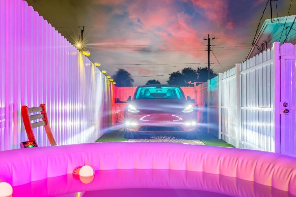 迈阿密花园Smart Tiny House Garden的一辆汽车在一条有粉红色栅栏的道路上行驶