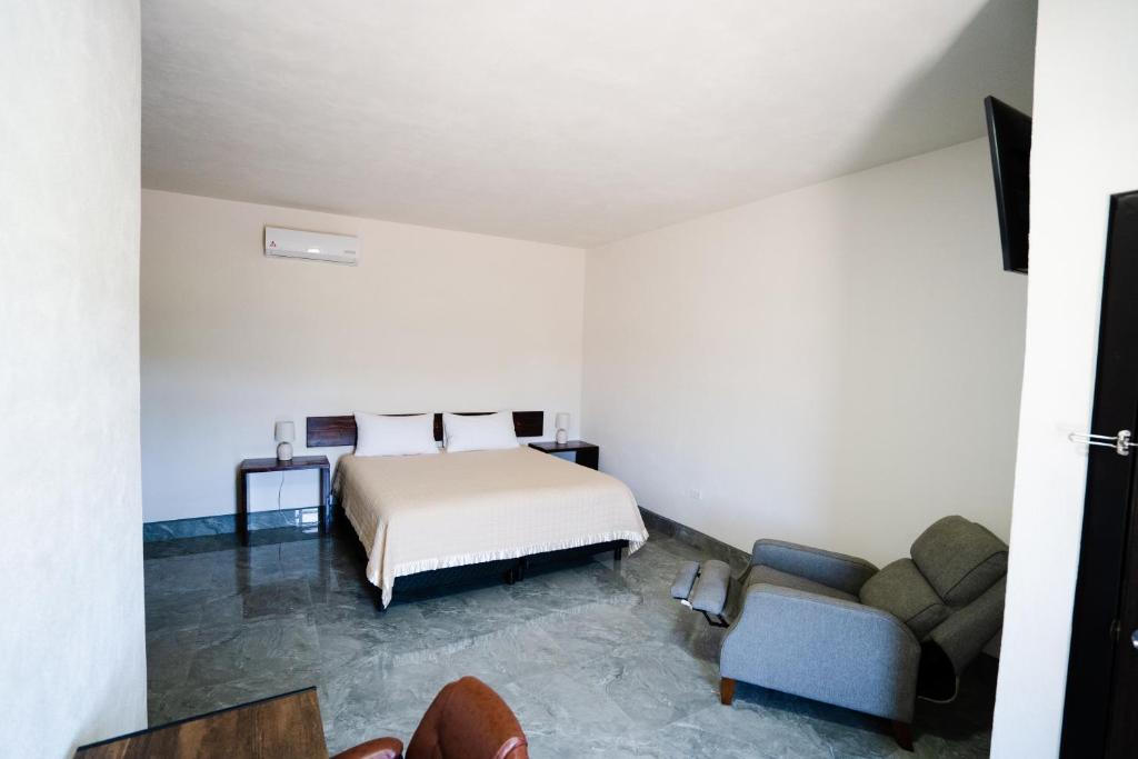 San QuintínHOTEL & RV PARK ROSA EVELYN的一间卧室配有一张床、一张沙发和一把椅子