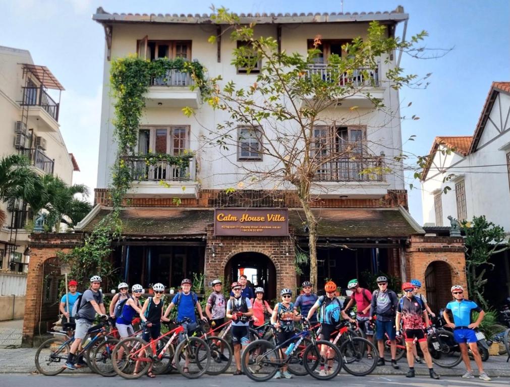 会安Calm House Hotel Hoi An 1的一群人骑着自行车在建筑物前