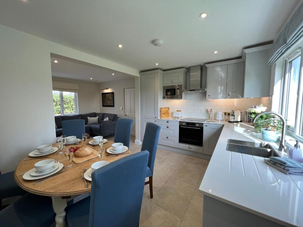BentleyDell View - Charming & Cosy的厨房以及带木桌和蓝色椅子的用餐室。