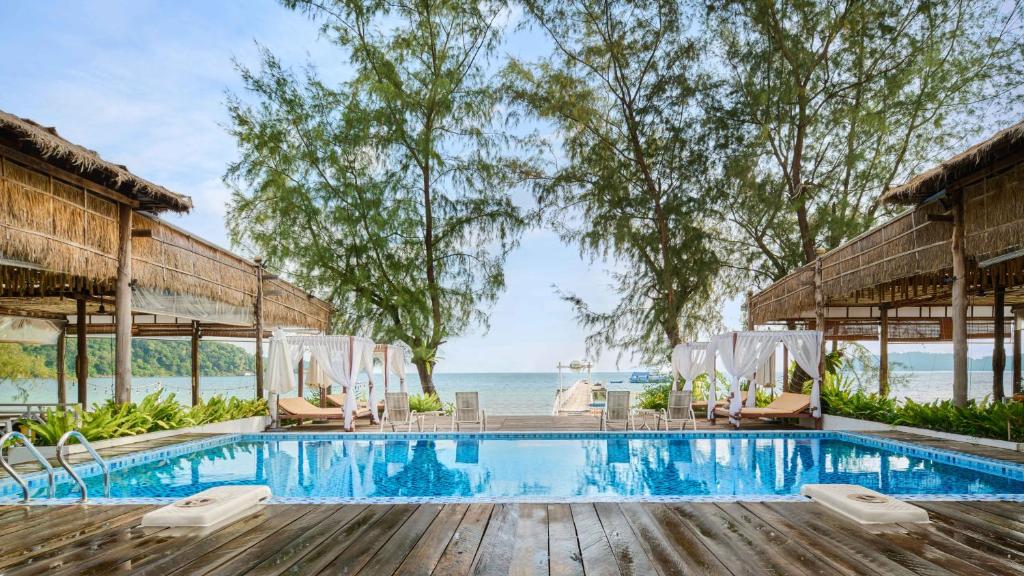 高龙撒冷岛Eden Beach Resort by EHM的一个带椅子的游泳池,背景是大海
