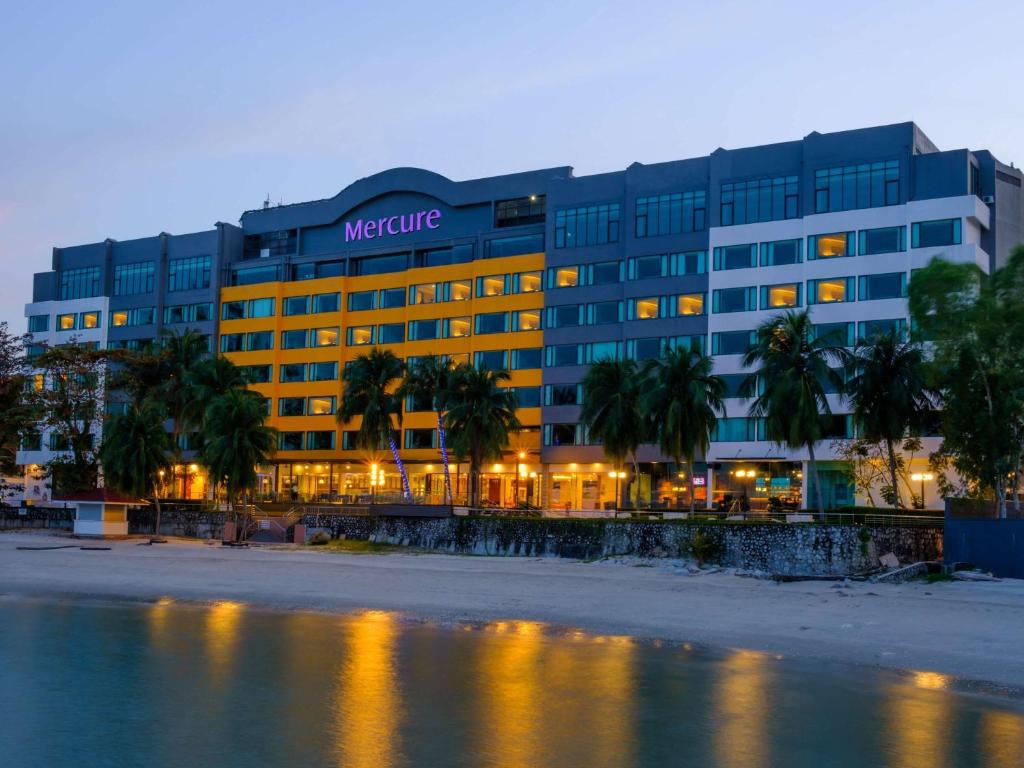 乔治市Mercure Penang Beach的一座大型办公楼,在水面上种有棕榈树