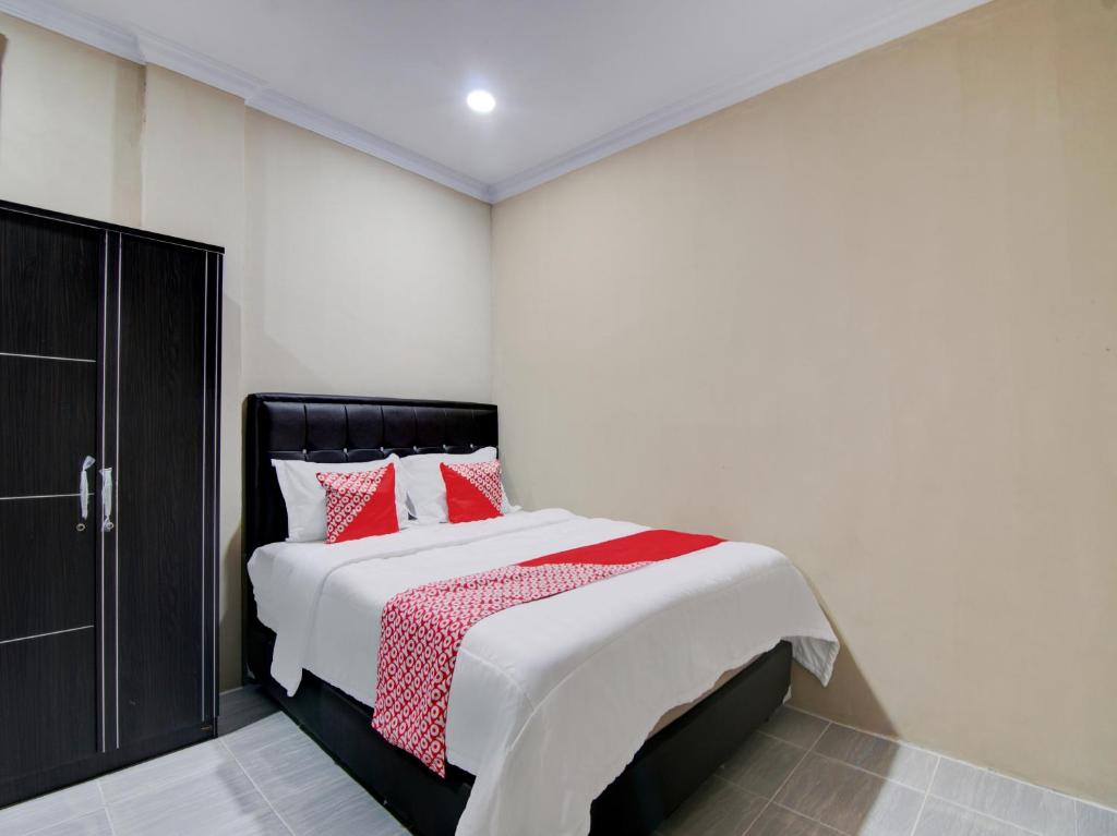 ParitOYO 93087 Wisma Apel Syariah的一间卧室配有一张带红色枕头的大床